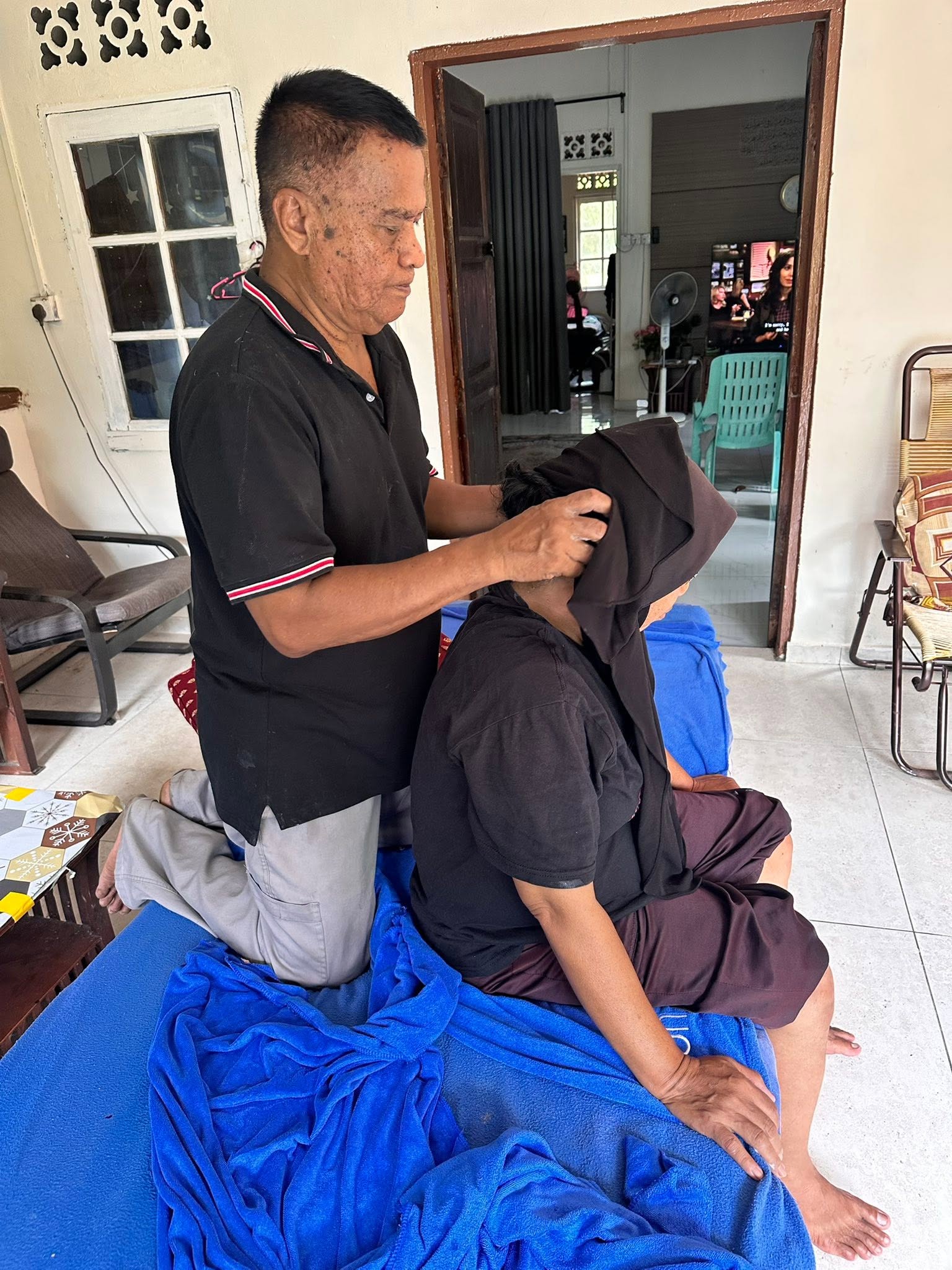 Pak Ali mengurut bahu dan leher seorang pelanggan wanita