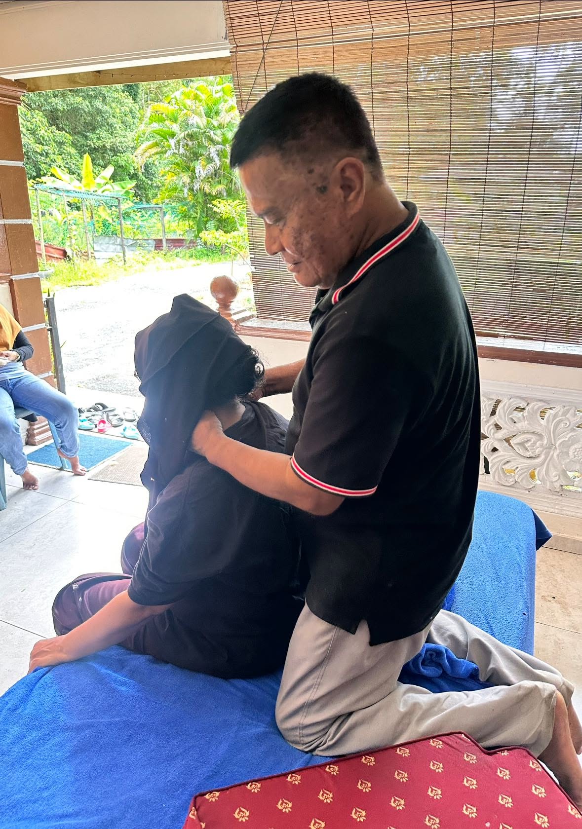 Pak Ali memberi tekanan urutan pada bahu pelanggan wanita